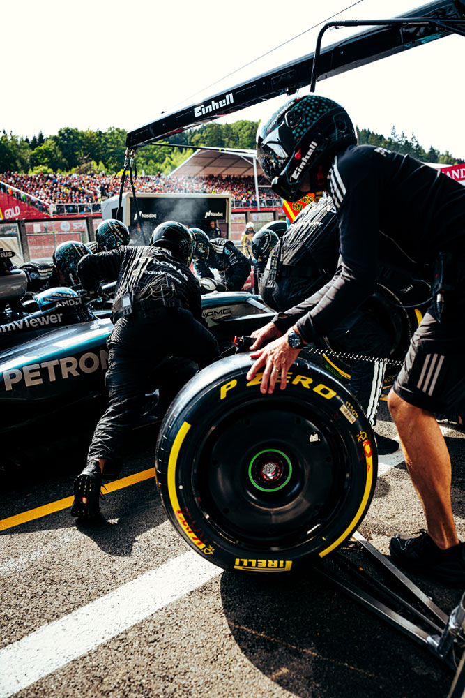 ช่างเทคนิคของทีม Mercedes-AMG PETRONAS Formula One Team กำลังดำเนินการหยุดรถในพิท หนึ่งในทีมกำลังเตรียมยาง Pirelli ในขณะที่คนอื่น ๆ ทำงานอยู่บนรถ โลโก้ Einhell ปรากฏอยู่บนอุปกรณ์เหนือรถ