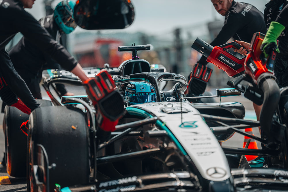 รถแข่งของทีม Mercedes-AMG PETRONAS Formula One Team ระหว่างการหยุดในพิท สมาชิกทีมใช้เครื่องเป่าลมไร้สายของ Einhell เพื่อช่วยระบายความร้อนให้กับชิ้นส่วนของรถ ทีมทำงานอย่างมุ่งมั่นและแม่นยำ