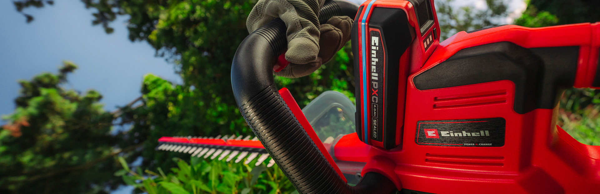 เครื่องตัดแต่งพุ่มไม้ไร้สาย Einhell กำลังตัดพุ่มไม้ในสวน