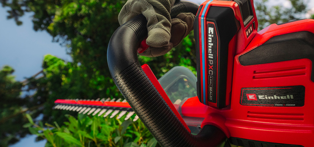 เครื่องตัดแต่งพุ่มไม้ไร้สาย Einhell กำลังตัดกิ่งไม้บนต้นไม้ในสวน