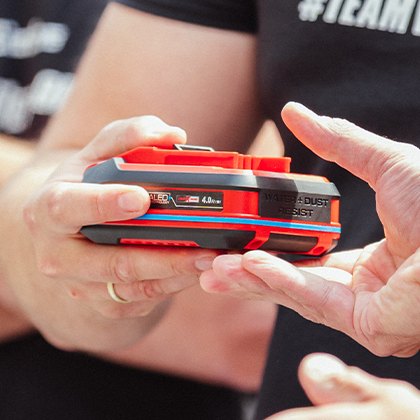 คนสองคนส่งมอบแบตเตอรี่ Einhell SEALED Power X-Change 4.0 Ah ให้กัน (ภาพสี)