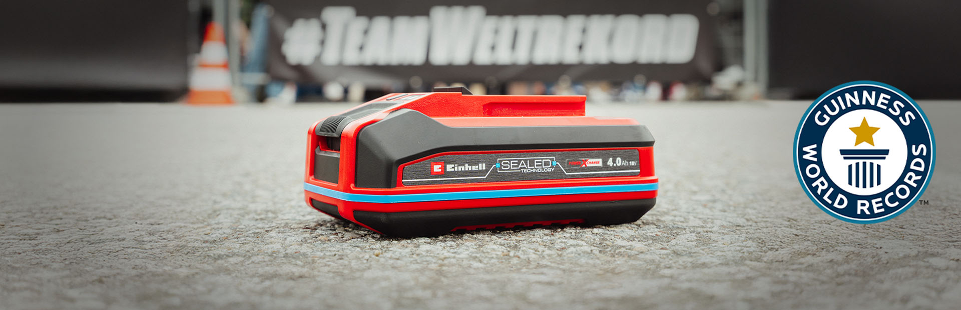 แบตเตอรี่ Einhell SEALED Power X-Change 4.0 Ah วางอยู่บนพื้น โดยมีโลโก้ Guinness World Records "Record Holder" อยู่ทางขวา